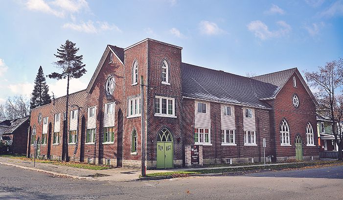 Maple Lodge: a red-brick former church with arched windows and a green door, on a sunny day
