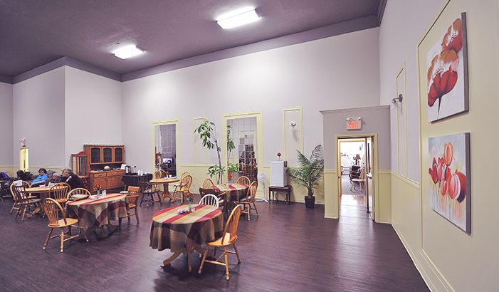 The dining room, with tables set for lunch under tall windows
